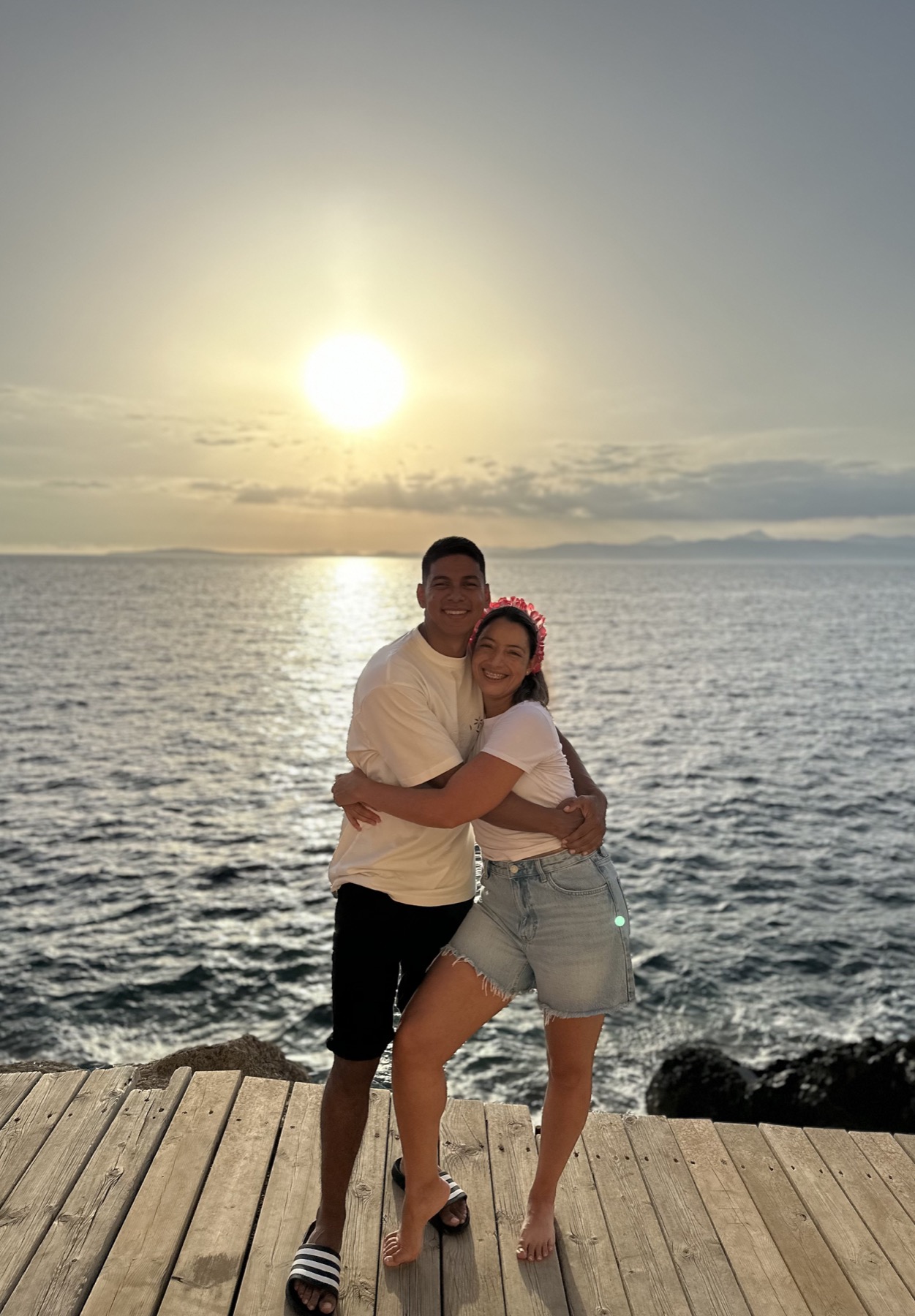 Laura y Lewis abrazados junto al mar al atardecer